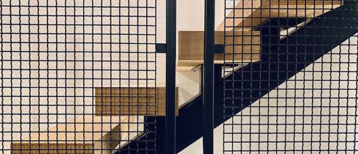 A close-up photo of staircase and railing that uses Wire Mesh Infill Panels.